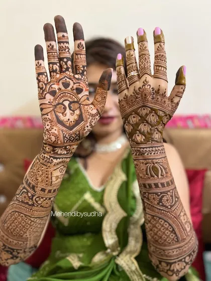 The lovely bride Divya showing off her full bridal mehendi, which features a mix of peacock motifs and geometric check patterns.