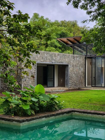 A view of the pool and stone-clad walls of a home in Alibaug. The design is about the essential elements: water, sun, plant life, and a simple, soulful home.