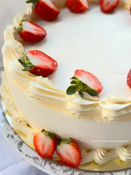 A close-up of a classic strawberry cake, showing the fresh cream and sliced strawberries.