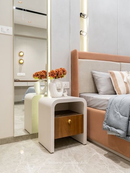 This serene bedside setup beautifully blends soft neutrals with a warm terracotta headboard, muted grey bedding, and a sleek marble flooring. The curved nightstand in PU white with a walnut drawer adds a chic contrast.