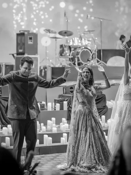 A candid black and white photo of the family enjoying the sangeet. It captures the pure, unchoreographed joy of the celebration.
