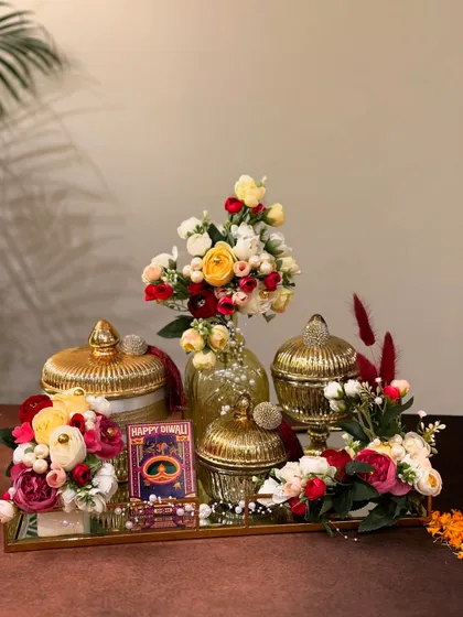 Our Diwali collection combines luxury with sustainability. This hamper, set on a mirror tray, features golden jars and a stunning floral arrangement, designed to add a touch of royalty to your celebrations.