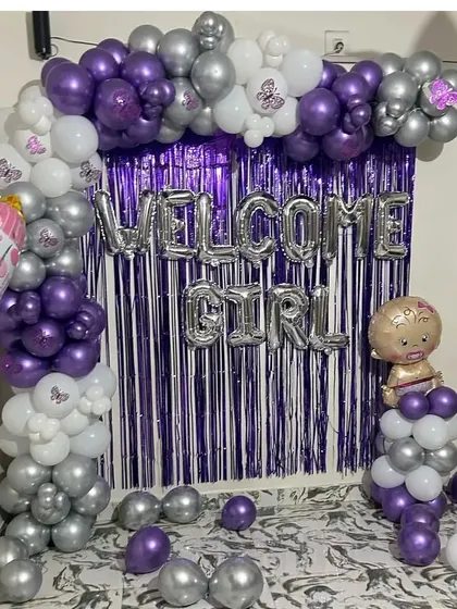 For a unique color combination, I used purple, silver, and white for this 'Welcome Girl' decoration. The tinsel curtain adds a touch of sparkle to the balloon arrangement.