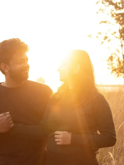 Holding hands and sharing a look in the warm, golden light. This simple, classic pose is all about their connection, framed by the beautiful, sunlit natural surroundings.