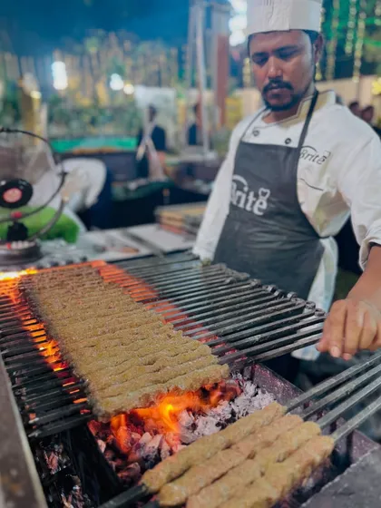 My chef carefully tends to long skewers of Mutton Seekh Kebabs, ensuring they are grilled evenly to juicy perfection.