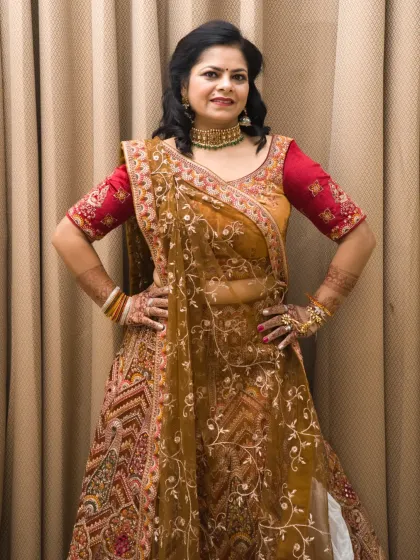 A full-length shot of the heavy bridal-style lehenga. The hands-on-hips pose is strong and classic for fashion photography.