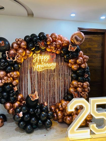 A clear, full shot of the 25th-anniversary decoration, showcasing the black and rose gold balloon arrangement with butterfly accents.