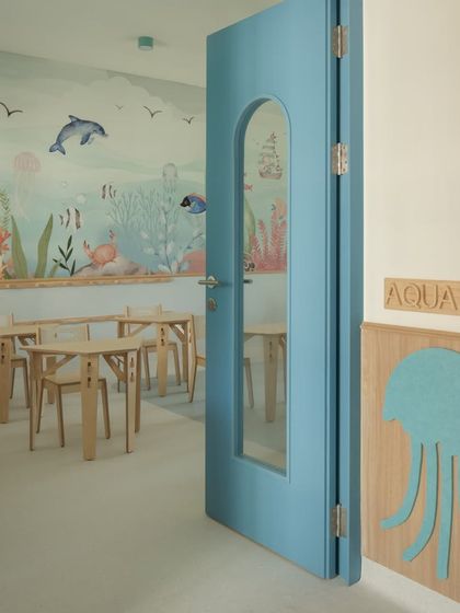 A jellyfish-shaped wooden cutout serves as a playful sign for an aqua-themed classroom. This small detail helps children navigate the school and feel a sense of ownership over their space.