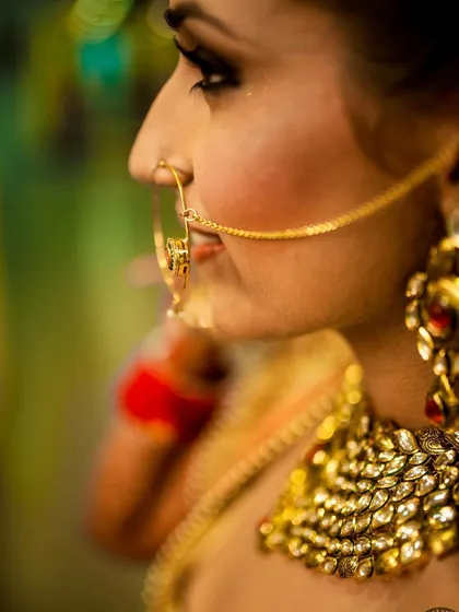 A detailed profile shot focusing on the bride's traditional nose ring and kundan necklace. I use a 35mm art lens to get close and capture the fine craftsmanship of the jewelry and the subtle expression of the bride.
