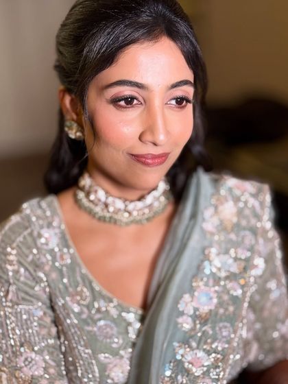 A soft and subtle reception look. The makeup focuses on rosy tones for the eyes and lips, complementing her beautiful pastel lehenga and intricate jewellery.