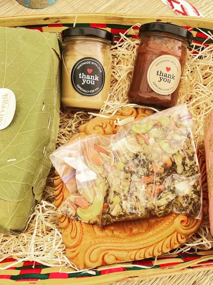 A close-up of my Diwali hamper, showcasing the eco-friendly packaging and the delicious treats inside. You can see the nut butters, trail mix, and a loaf of bread wrapped in a leaf.