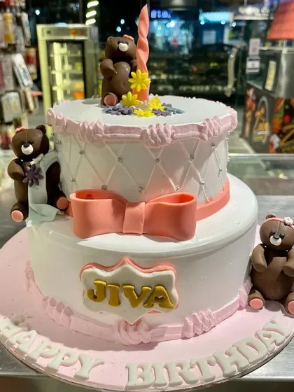 A lovely two-tier teddy bear themed cake. With its quilted pattern, delicate pink bow, and adorable fondant bears, this cake is a heartwarming choice for a young child's birthday or baby shower.