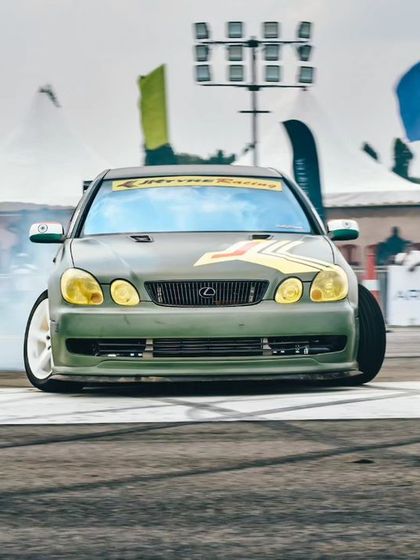 The Lexus drift car, with its distinctive yellow headlights, seen from the front as it slides through a corner. The skill and car control on display are simply mesmerizing.