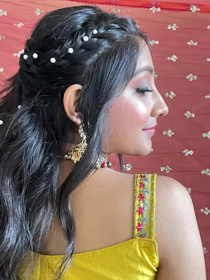 A side view of this pretty bridesmaid look. The makeup is soft and enhances her natural beauty, while the pearl-studded hair adds a special touch.