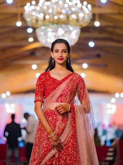 For this client attending her brother's engagement, we chose a sophisticated and elegant look. The makeup features a classic red lip and defined eyes, paired with soft, side-parted hair that beautifully complements her stunning red lehenga.