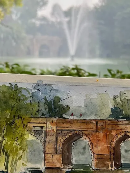 My sketchbook at Lodhi Garden, with the Athpula bridge sketch in progress and the misty fountain in the background.