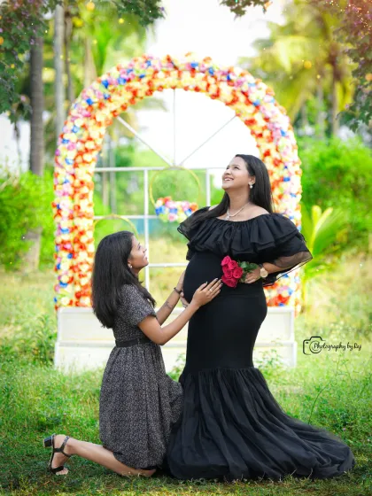 A joyful moment between a mother-to-be and her friend, who is kneeling to talk to the baby bump.