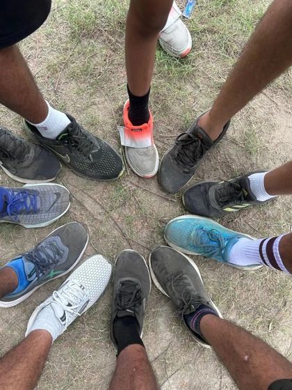 A classic runners' circle, showing the variety of running shoes and the unity of the team. We are all connected by the path we run.