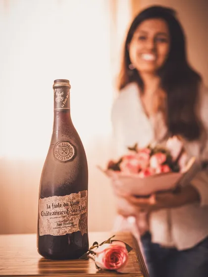 A lifestyle shot with me in the background, holding roses, with the vintage wine bottle in focus. This adds a personal, behind-the-scenes touch to the romantic theme.