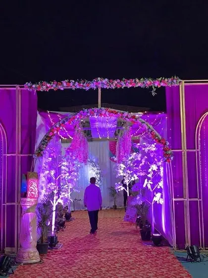 A grand entrance structure for a purple-themed wedding. The multiple arches, chandeliers, and dramatic lighting set an impressive tone for the event.