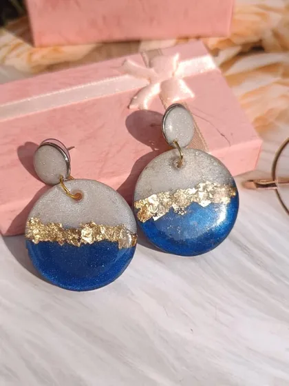 These beautiful round earrings feature a classic design of royal blue and shimmering white resin, accented with gold flakes. They are handmade and perfect for any occasion.