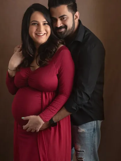 This is a classic couple maternity portrait that shows the connection between partners. The gentle embrace and happy smiles tell a story of a shared journey into parenthood.