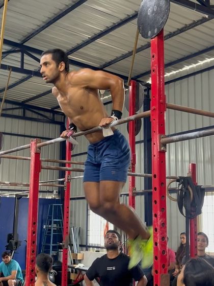 A competitor executing a perfect bar muscle-up. Our training prepares athletes for high-skill movements in a competitive environment.
