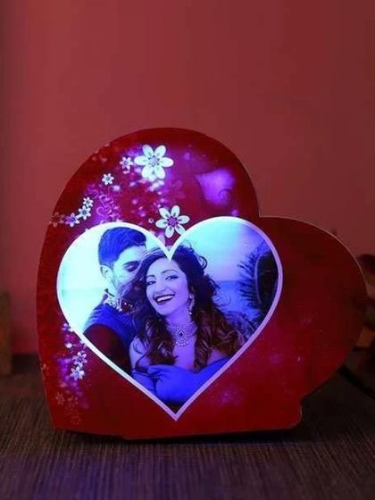 This heart-shaped LED lamp holds a photo of a couple, surrounded by a floral design. It glows with a soft light, making it a wonderful romantic gift for Valentine's Day or an anniversary.