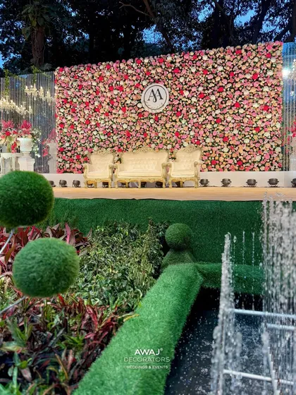 A view of the grand stage from across the garden fountain, showcasing the scale of the floral backdrop and the beautiful surrounding landscape.