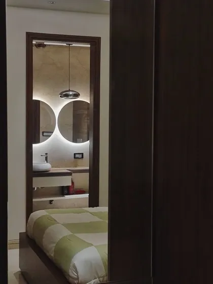 A carefully framed view from a bedroom into the ensuite washroom. This shot demonstrates how we create seamless transitions between spaces, with the washroom's modern lighting and dual mirrors acting as a design feature visible from the bed.
