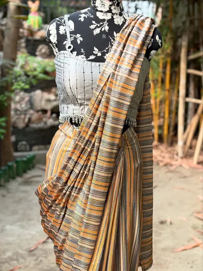 A close-up of the draped striped saree, showing the texture of the fabric and the detailed tassels on the blouse.