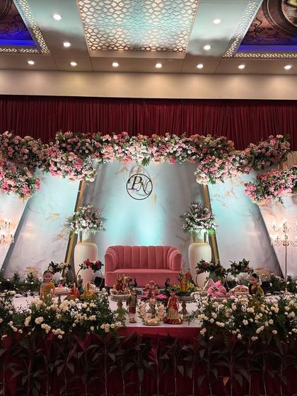 A modern engagement stage with a backdrop of geometric marble-patterned panels and lush floral arrangements. The design is chic and sophisticated, perfect for a contemporary celebration.