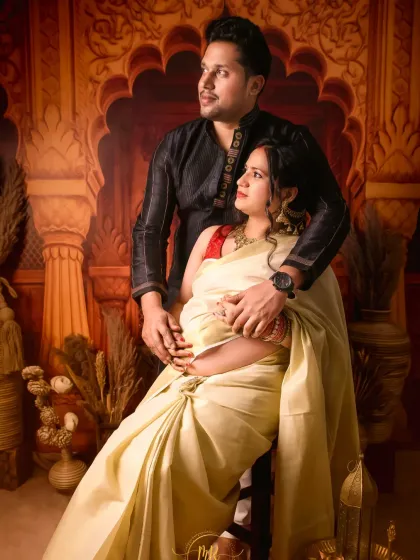 A beautiful couple's portrait in traditional Indian attire. The partner embraces his wife, who is wearing an elegant white and gold saree, creating a timeless and cultural photo.
