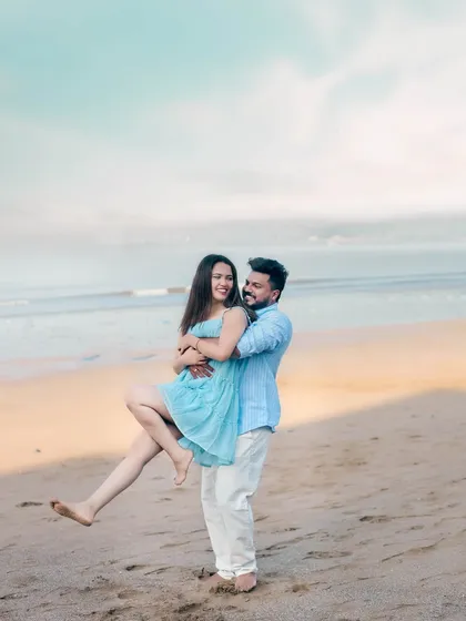 A fun and candid shot of a couple on the beach, with the groom playfully lifting the bride, capturing their joyful energy.
