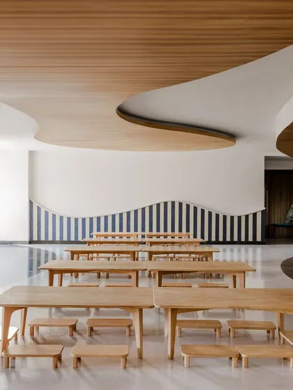 A multi-purpose hall at Vedanya School with a curved ceiling and striped wall. The design reflects the way children learn and move, free from rigid boundaries and full of opportunities for exploration.