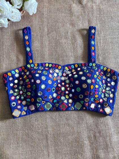 This royal blue blouse is ready for any festival. It's covered in colorful mirror work and beads, with a modern spaghetti strap design.