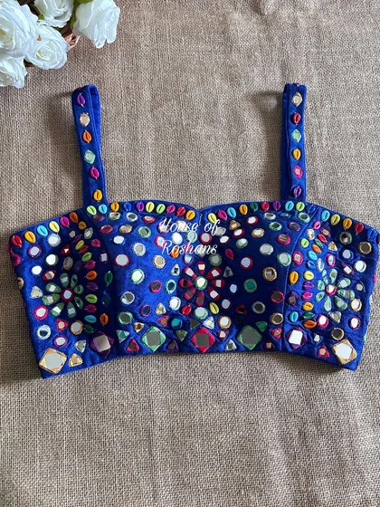 This royal blue blouse is ready for any festival. It's covered in colorful mirror work and beads, with a modern spaghetti strap design.