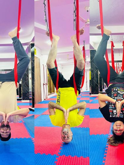 Inversions are a cornerstone of aerial yoga. This trio of students practices a synchronized inverted prayer pose, building strength, focus, and a sense of community.