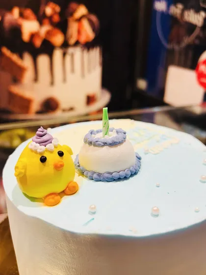 A close-up of a cute fondant chick and a mini birthday cake, perfect as toppers for a larger cake.