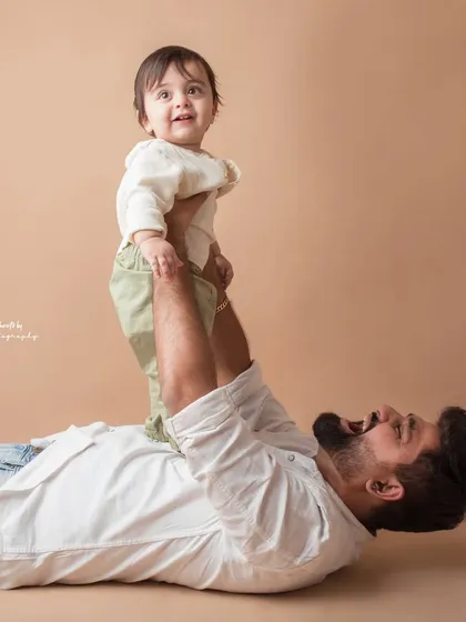 A father's playful spirit comes alive in this shot, lifting his son up high. The joy on both their faces is priceless.