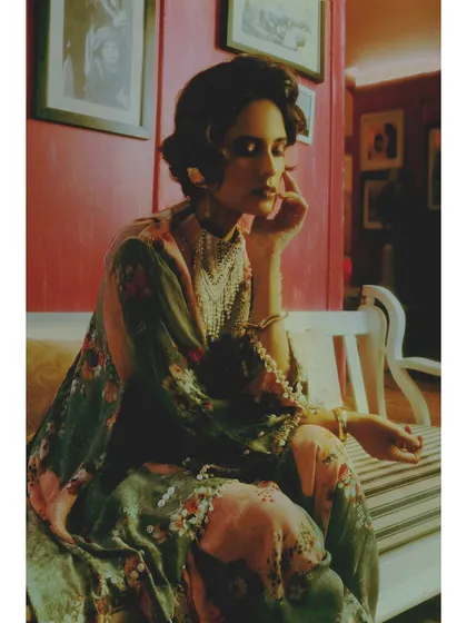 A moment of quiet contemplation. The soft lighting and the intricate pearl details on the floral outfit highlight the romantic nostalgia that still lingers.