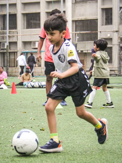 A player dribbles with determination, his eyes focused on the ball as he moves across the turf during a practice session.