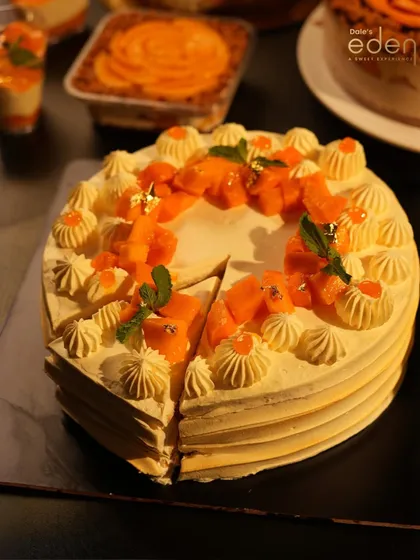 A table of tropical dreams. Our Mango Cream Cake, sliced and ready to serve, surrounded by other mango-themed treats from our seasonal menu.