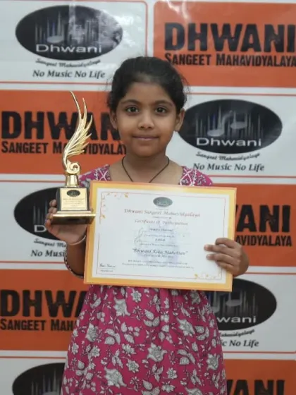 A young girl proudly holds her certificate and trophy.