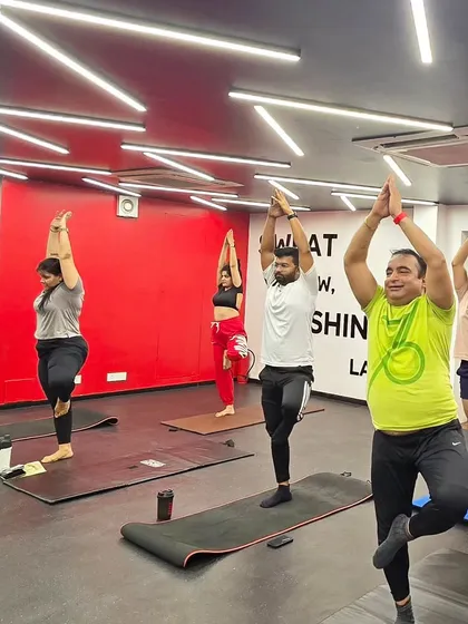 Students holding Vrikshasana (Tree Pose). This balancing posture significantly improves concentration and strengthens the legs, while also helping to open the hips.