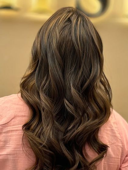 A back view of a client's hair after a highlighting service. The rich tones and soft waves create a beautiful, dimensional look with a healthy shine.