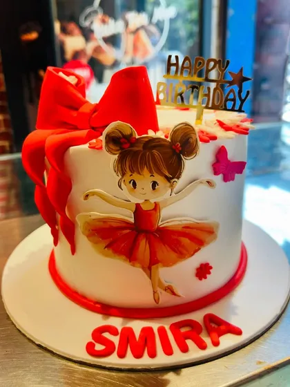 A sweet ballerina-themed cake with a big red bow for a little dancer's birthday.