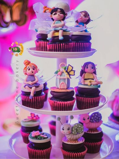 The full cupcake tower from the enchanted forest party. It showcases a variety of toppers, from different fairies to snails and butterfly houses, creating a stunning and cohesive display.