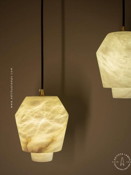 A close-up detail of the marble pendant, showing the subtle gold accent and the soft, warm light that filters through the stone.