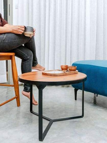 A classic wooden bar stool with a backrest, a sleek metal-framed coffee table, and a vibrant blue pouf, all designed by us for the T7 T8 project.